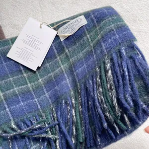 Detail of 100% pure wool plaid scarf featuring blue-green weave, fringes and brand label