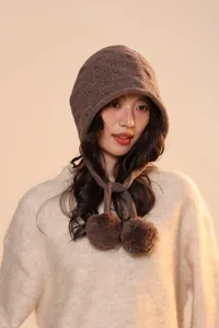 Close-up of dark brown wool knit hat with intricate texture and pom-pom ties