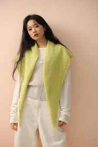 Detail of soft lemon green knitted shawl draped over white outfit for spring wear
