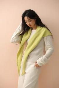 Detail showing soft knit fabric texture of a pale yellow shawl in a cozy indoor setting