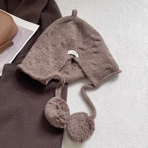 Close-up of 100% wool knit hat featuring soft texture and decorative pom-pom details