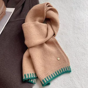 Detailed close-up of wool blend knit scarf featuring green stripes and gold logo plate