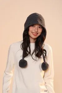 Close-up of deep grey wool knit trapper hat with fluffy pom-poms and ear protection