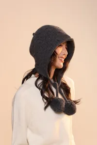Detail of dark grey 100% wool knit trapper hat with soft pom-poms and warm ear flaps