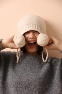 Textura detallada de punto de un gorro de lana con pompones suaves y lazos para atar
