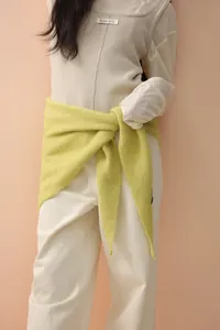 Detail of light green knitted shawl over cream vest with visible brand label