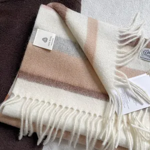 Detail of 100% handmade wool scarf featuring striped texture, fringe and fabric label