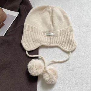 Gorro de punto 100% lana con pompones y orejeras en color blanco crema