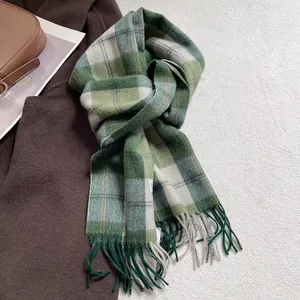 Detalle de bufanda de lana suave con cuadros verdes y flecos en abrigo marrón