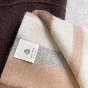 Detail of 100% wool scarf showing handmade label and striped texture in blue and beige
