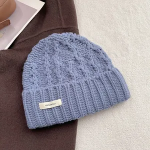 Detailansicht der blauen Wollstrickmütze mit Zopfmuster und 100% Wolle Etikett