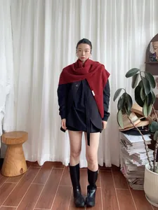 Detail of a bright red 100% wool triangle scarf paired with a black winter coat