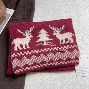 Detail of red knitted wool scarf with festive reindeer pattern and premium leather tag