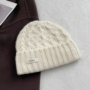 Detail einer grob gestrickten Beanie aus 100% Wolle mit Etikett und Strickstruktur