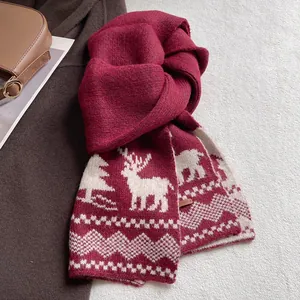 Detail of red Christmas knit scarf featuring white reindeer patterns and festive textures