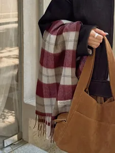 Detalle de bufanda de lana a cuadros con flecos y bolso tote marrón con un look otoñal