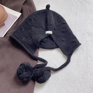 Detail of black 100% wool knit trapper hat showing soft texture and cozy pompom ties