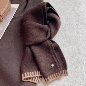Detailed close-up of dark brown wool blend scarf with ribbed edges and metallic logo tag