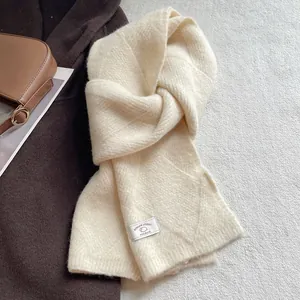 Detail eines cremeweißen Strickschals aus Wollmischung mit Kreuzdurchzug-Design