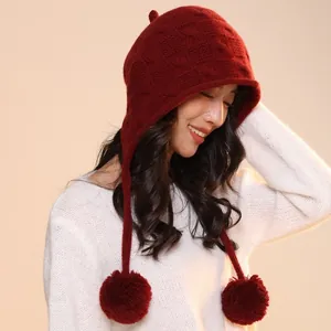 Deep red waffle knit trapper hat with pom-poms shown on model for autumn winter style