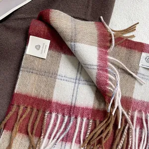 Detalle de bufanda de lana 100% a cuadros británicos con flecos granates y caquis