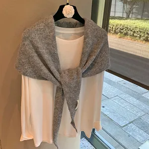 Detailed texture of a dark grey knit shawl draped over a basic white long-sleeve tee