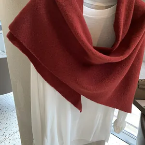 Macro detail of soft red knitted wool shawl texture styled on a white outfit