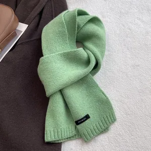 Detail of light green 100% wool scarf showing knit texture and premium material label
