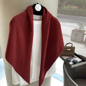 Detail of burgundy wool knit shawl on hanger showing soft texture and drape quality