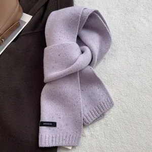 Detail showing 100% wool label on light purple knitted scarf with mélange effect