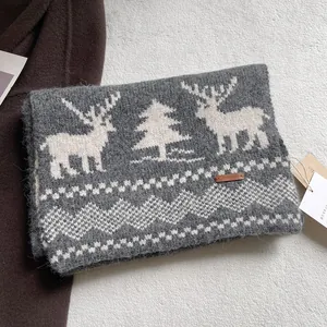 Close-up of grey knit wool scarf with white reindeer patterns and leather tag
