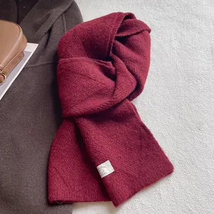 Detaillierte Makroansicht der Wollmischung und des genähten Etiketts auf dem roten Strickschal