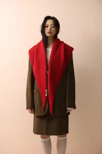Detail of a bright red knitted shawl styled over a classic brown checkered blazer set