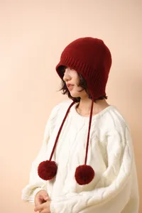 Detalle de gorro de lana roja con orejeras, pompón y cordón para el invierno