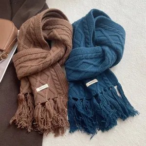 Detail of 100% wool scarves with cable knit texture and fringe in brown and navy colors