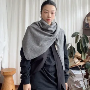 Detailed view of grey 100% wool triangle scarf draped over a black knit top