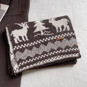 Detail of Nordic knit scarf with reindeer patterns and premium leather logo patch