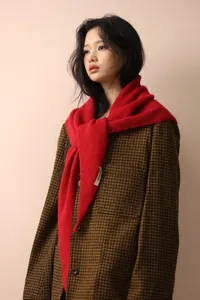 Detail of dark red knitted shawl paired with a classic brown plaid blazer and label