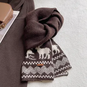 Detail of retro knit scarf featuring white elk patterns and a brown leather brand tag