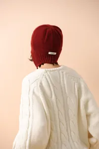 Detalle del gorro de punto 100% lana con textura burdeos y etiqueta de material