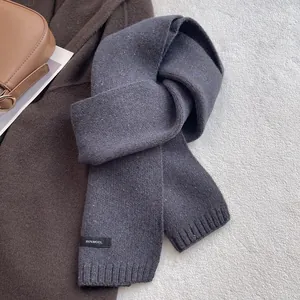Detail showing the 100% wool knit texture and ribbed edge of the navy blue scarf