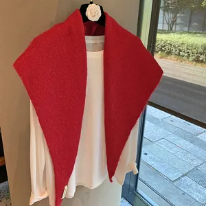 Close-up of bright red mohair knit shawl with soft fluffy texture over white top