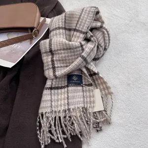 Detail of wool blend plaid scarf featuring brown fringe and a woven brand label