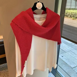 Close-up of red mohair knit shawl with plush texture and white woven label detail