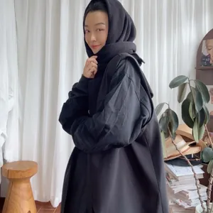 Close-up of a minimalist black hooded wool cape showing high-quality woven fabric texture