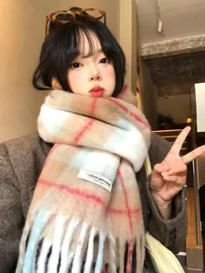 Close-up of thick plaid wool blend scarf featuring soft fringes and a stitched fabric label