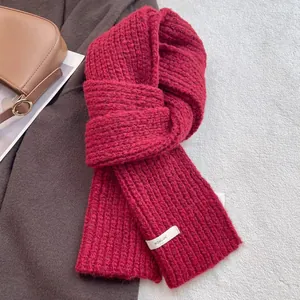 Close-up of chunky burgundy wool scarf with knit texture and BOWLOW brand label