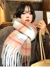 Close-up of thick plaid wool blend scarf with fringe detail and woven patch on dark coat