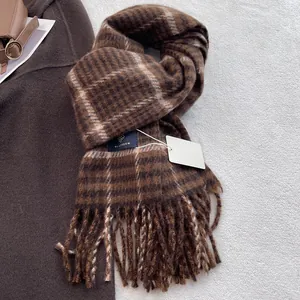 Detail of wool blend plaid scarf with tassels, leather bag, and warm winter layers