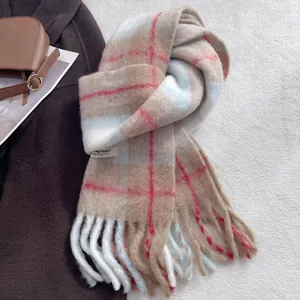Detail of plaid wool blend scarf with fringe edges and brand label on grey texture